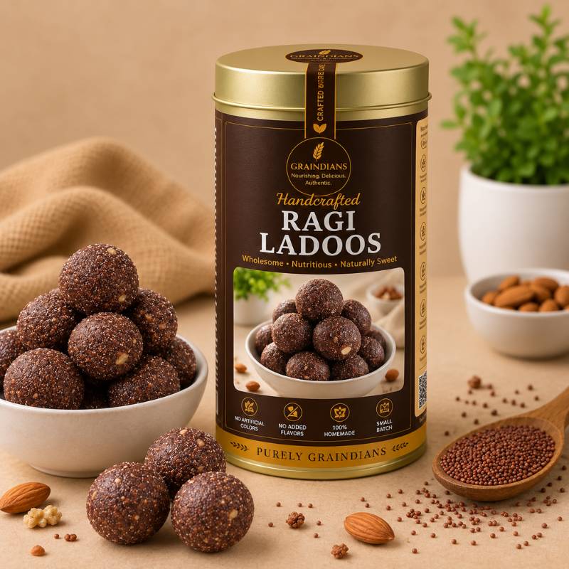 Graindians Homemade Ragi Ladoos in premium gift tin with fresh ragi ladoos, almonds and finger millet displayed on a beige background.